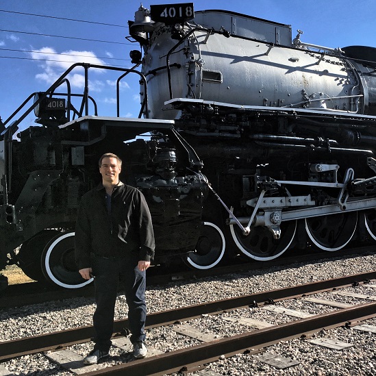 John Krueger standing in front of a historic steam locomotive